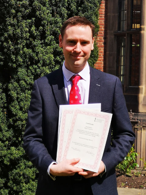 Nigel Copland holding award certificates