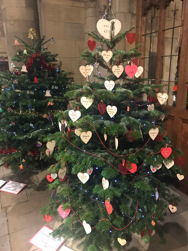A christmas tree with heart decorations and other sentimental pieces
