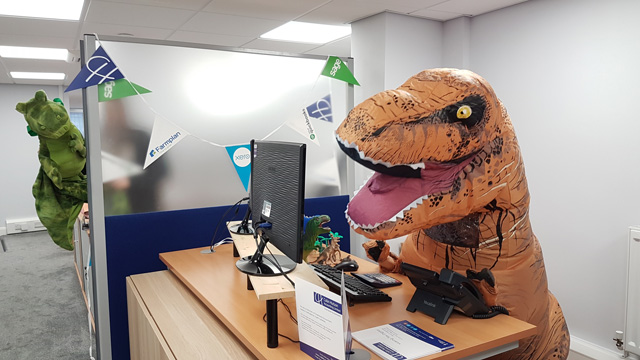 A T-rex answering the phone at an office desk